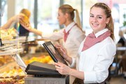 Shopkeeper or saleswoman at bakery working at cash register